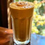 Close-up view of a creamy pumpkin smoothie in a glass with a straw.