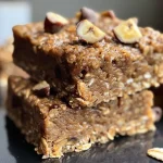 Close-up of golden brown banana oatmeal breakfast bars with oats sprinkled on top.