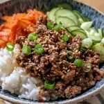 Close-up view of a Korean Beef Rice Bowl featuring minced beef, vegetables, and garnishes.