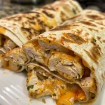 A close-up view of crispy chicken and cheese wraps on a rustic wooden surface.