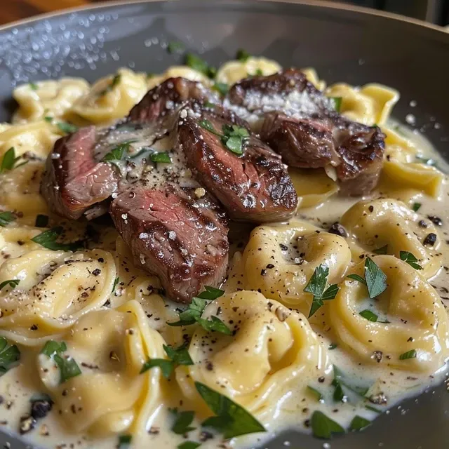 Side view of a plate filled with creamy garlic steak tortellini, garnished with parsley.