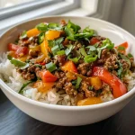 Close-up view of a beef and pepper rice bowl with colorful bell peppers and ground beef.