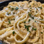 Close-up view of creamy garlic pasta with a sprinkle of parsley.