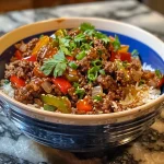 Close-up view of a beef and pepper rice bowl, showcasing colorful ingredients.