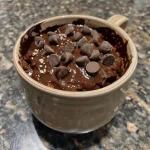Close-up of a fluffy, low-calorie chocolate mug cake topped with chocolate chips.