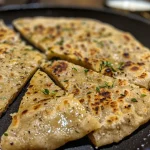Close-up view of gluten-free flatbread on a wooden board, showcasing its texture.