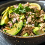 Close-up view of a colorful avocado tuna salad in a bowl.