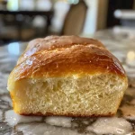 Close-up of a golden-brown loaf of homemade bread with a soft crust.