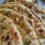 Close-up view of homemade flatbread showing a golden-brown surface with a sprinkle of herbs.