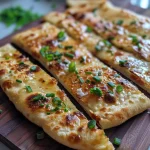 Close-up of fluffy flatbread with a golden-brown exterior, sprinkled with green onions.