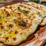 A close-up side view of freshly baked homemade flatbread with a golden-brown crust.