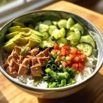 Close-up view of a Tuna Rice Bowl with diced avocado and cucumber.