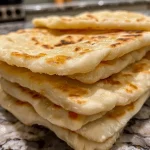 Close-up of soft, fluffy Greek pita bread with a golden-brown exterior.