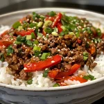 A close-up view of a Beef and Pepper Rice Bowl featuring ground beef, diced red bell pepper, and green onions over white rice.