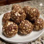 A close-up view of chocolate almond butter energy balls on a white plate.