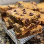 A close-up side view of warm chocolate chip cookie bars with melted chocolate.
