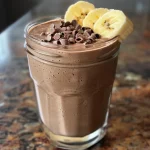 A close-up view of a creamy chocolate peanut butter banana smoothie in a glass.