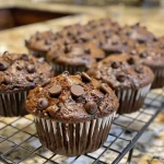 Close-up side view of freshly baked double chocolate chip muffins with melted chocolate chips.