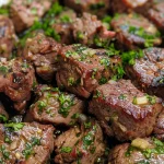 Close-up of juicy garlic butter steak bites garnished with parsley.