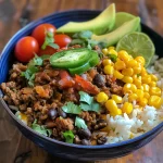Close-up view of a Ground Beef Taco Rice Bowl garnished with avocado and cherry tomatoes.