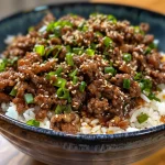 Juicy ground beef teriyaki in a bowl, garnished with sesame seeds and green onions.
