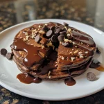 Close-up of fluffy chocolate pancakes topped with chocolate chips.