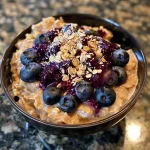 Close-up side view of High Protein Blueberry Overnight Oats in a glass jar.