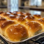 Close-up of golden-brown homemade dinner rolls arranged on a plate.