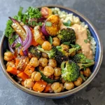A vibrant bowl filled with roasted vegetables and chickpeas, featuring colorful zucchini, carrots, and broccoli.