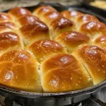 Close-up view of golden-brown skillet dinner rolls with a glossy top.