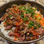 A close-up side view of a bowl filled with spicy Korean beef, garnished with green onions and sesame seeds.