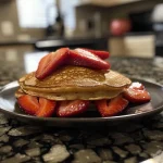 Close-up of fluffy strawberry Greek yogurt pancakes stacked on a plate.