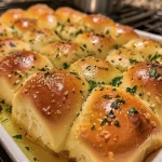Close-up view of soft garlic and herb dinner rolls with melted butter on top.