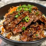 Close-up view of a Spicy Beef Rice Bowl topped with green onions and sesame seeds.