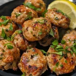 ['Close-up view of golden-brown air fryer turkey bites garnished with herbs and lemon zest.', 'Juicy turkey bites cooked in an air fryer, showing a crispy exterior and fresh herbs.', 'Side view photo of flavorful turkey bites, highlighting their juicy texture and vibrant herbs.', 'Appetizing air fryer turkey bites displayed with a sprinkle of parsley and a lemon wedge.']