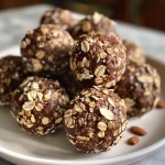 ['Close-up of almond espresso energy bites on a rustic wooden table.', 'Side view of a cluster of almond espresso energy bites with visible ingredients.', 'Juicy almond espresso energy bites showcasing slivered almonds and a glossy surface.', 'Delicious almond espresso energy bites with a textured appearance, resting on a plate.']