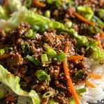 ['Close-up of juicy Asian Style Ground Beef Lettuce Wraps topped with sesame seeds on a plate.', 'Side view of fresh lettuce wraps filled with seasoned ground beef, colorful vegetables, and garnished with green onions.', 'Succulent lettuce wraps featuring ground beef, shredded carrots, and bell pepper, displayed on a wooden table.', 'Plate of Asian Style Ground Beef Lettuce Wraps drizzled with sauce and arranged with vibrant ingredients.']