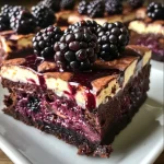['Close-up side view of Blackberry Cheesecake Brownies with a rich, fudgy texture and visible blackberries.', 'Detailed image of Blackberry Cheesecake Brownies showcasing the creamy cheesecake layer and chocolate base.', 'A slice of Blackberry Cheesecake Brownie viewed from the side, highlighting its decadent layers and berry toppings.', 'Side view of moist Blackberry Cheesecake Brownies, featuring a glossy chocolate top and fresh blackberries.']