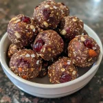 ['Close-up view of chocolate cherry energy bites with a glossy surface.', 'Side view of bite-sized chocolate cherry energy balls topped with chocolate chips.', 'Juicy chocolate cherry energy bites showcased on a light background.', 'Gourmet chocolate cherry energy balls displayed in a rustic setting.']