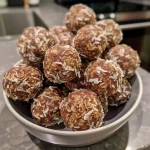 ['Close-up side view of coconut mocha energy balls with a glistening chocolate surface.', 'Delicious coconut mocha energy balls displayed on a rustic wooden surface.', 'Side perspective of energy balls, showcasing coconut flakes and rich cocoa texture.', 'A tempting arrangement of energy balls with visible coconut and chocolate layers.']