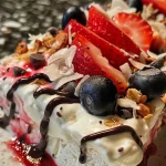 ['Close-up view of frozen yogurt bark topped with strawberries, blueberries, granola, coconut flakes, and chocolate chips.', 'Side view of colorful frozen yogurt bark displaying fresh fruits and toppings.', 'Juicy frozen yogurt bark with a variety of toppings, including berries and granola.', 'Vibrant frozen yogurt bark featuring a mix of strawberries, blueberries, and chocolate.']
