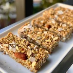 ['Close-up view of gluten-free granola bars with visible nuts and seeds.', 'Side perspective of chewy granola bars showcasing ingredients like almonds and coconut.', 'Delicious-looking gluten-free granola bars featuring a mix of seeds and nuts.', 'Textured granola bars highlighted with chunks of almonds and pumpkin seeds.']