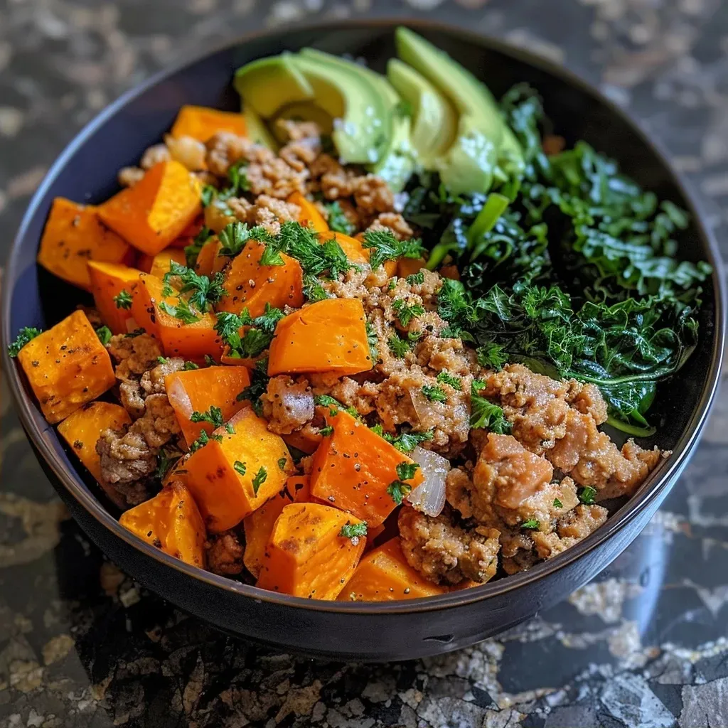 A colorful bowl filled with ground turkey, diced sweet potatoes, and fresh greens.