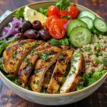 ['Close-up view of a Mediterranean chicken bowl with vibrant vegetables and quinoa.', 'Side view of a healthy, high-protein chicken bowl featuring colorful ingredients and Greek yogurt.', 'Juicy chicken breast atop a bed of quinoa and fresh lettuce in a Mediterranean-style bowl.', 'Detailed shot of a nutritious chicken salad bowl garnished with olives and tomatoes.']