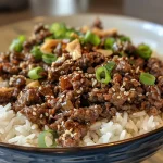 ['Close-up view of a Korean Ground Beef Bowl featuring ground beef, rice, and toppings.', 'Side perspective of a delicious Korean Ground Beef Bowl with glossy beef and colorful toppings.', 'Juicy Korean Ground Beef Bowl displayed with rice, minced garlic, and vibrant garnishes.', 'Detailed shot of a Korean Ground Beef Bowl showcasing the rich textures of beef and rice.']
