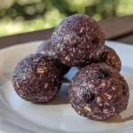 ['Close-up view of low calorie blueberry protein balls, showcasing their round shape and vibrant blue color.', 'Juicy blueberry protein balls arranged side by side, highlighting their texture and ingredients.', 'Side view of several blueberry protein balls, emphasizing their natural color and healthy composition.', 'Tasty low calorie protein balls filled with blueberries, displayed with a soft focus background.']