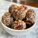 ['Close-up view of homemade Maple Pecan Energy Balls with a glistening texture.', 'Side view of Maple Pecan Energy Balls showcasing their chunky ingredients and rich color.', 'Detailed image of Maple Pecan Energy Balls highlighting oats and pecans.', 'Juicy Maple Pecan Energy Balls arranged attractively, capturing their delicious appeal.']