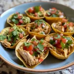 ['Close-up of Mini Chicken Taco Cups arranged on a plate with toppings.', 'Side view of delicious Mini Chicken Taco Cups garnished with cilantro.', 'Juicy Mini Chicken Taco Cups filled with shredded chicken and salsa.', 'Handheld Mini Chicken Taco Cups showcasing vibrant ingredients.']