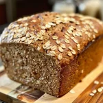 ['Side view of a freshly baked multigrain buttermilk bread, showcasing its crust and texture.', 'Close-up shot of multigrain buttermilk bread with visible seeds and grains, highlighting its rustic look.', 'Detailed angle of multigrain buttermilk bread, emphasizing the variety of seeds and whole grains used.', 'Juicy slice of multigrain buttermilk bread with a golden crust and a rich, textured interior.']