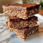 ['Close-up view of No Bake Chocolate Coconut Bars showing layers of chocolate and coconut.', 'Side view of delicious No Bake Chocolate Coconut Bars with a glossy chocolate finish.', 'Juicy No Bake Chocolate Coconut Bars stacked, featuring a mix of chocolate and coconut textures.', 'Rich No Bake Chocolate Coconut Bars displayed on a plate, highlighting the ingredients within.']